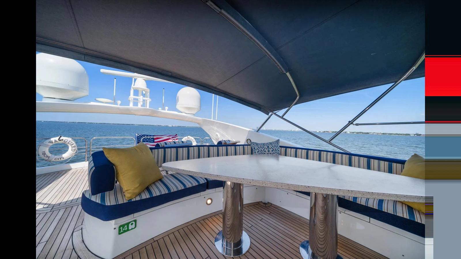 The flybridge offers a shaded seating area with a table, perfect for enjoying the view. aboard VANGUARD Yacht for Sale