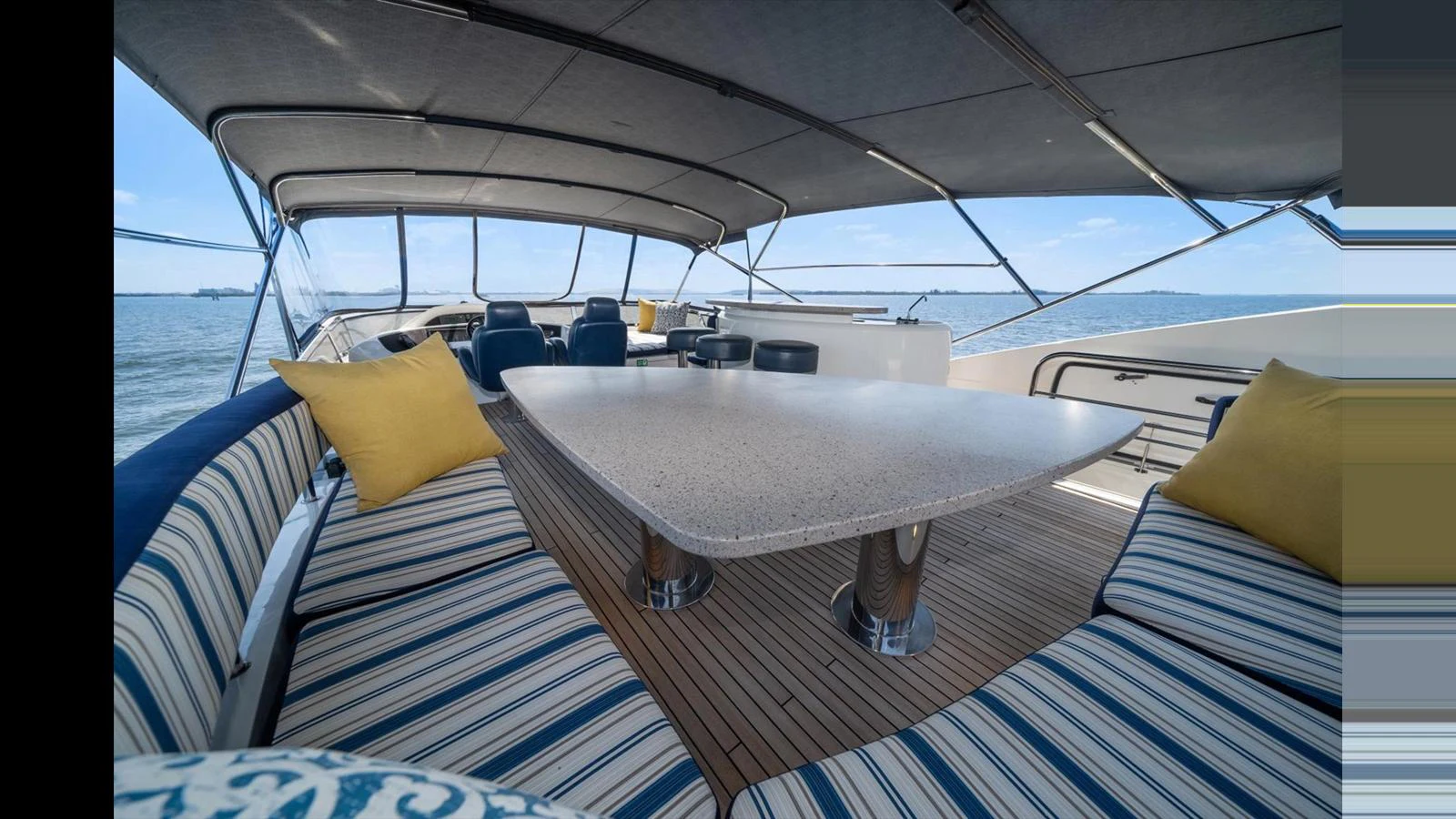 The flybridge offers a spacious and shaded area with comfortable seating and a large table for outdoor dining. aboard VANGUARD Yacht for Sale