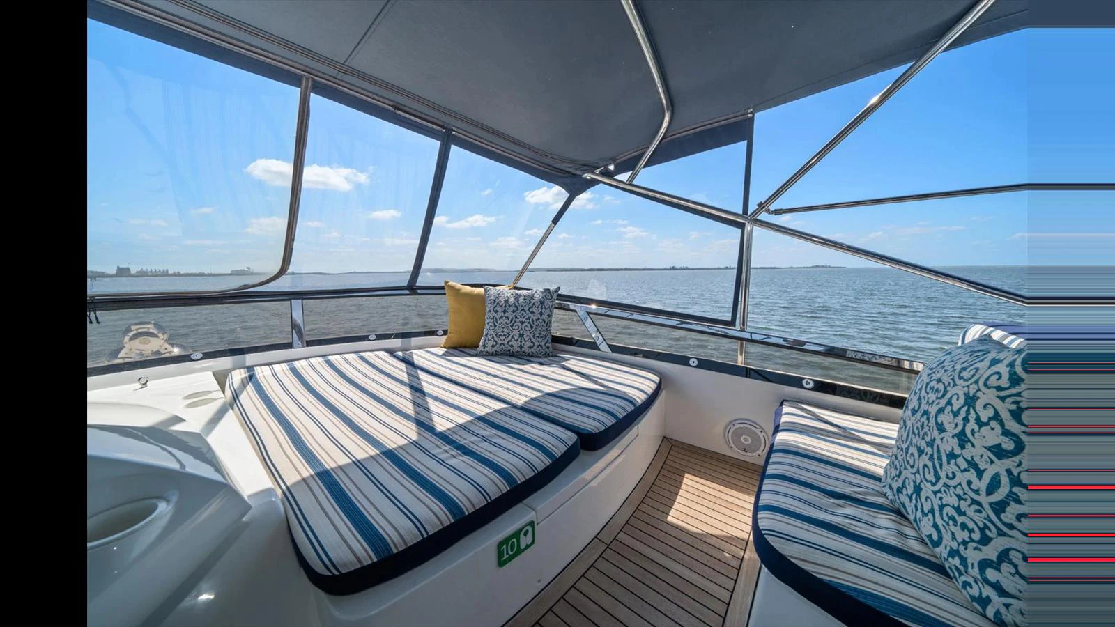 The flybridge offers a comfortable lounging area with striped cushions and panoramic views of the water. aboard VANGUARD Yacht for Sale