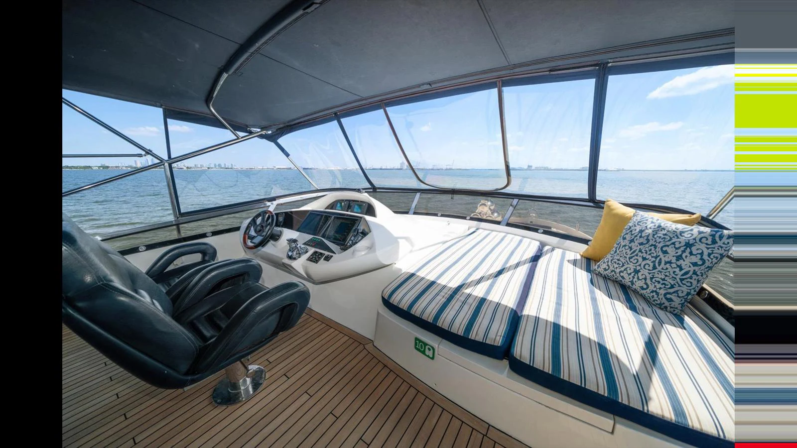 The helm area features a comfortable seating arrangement with panoramic views of the water. aboard VANGUARD Yacht for Sale