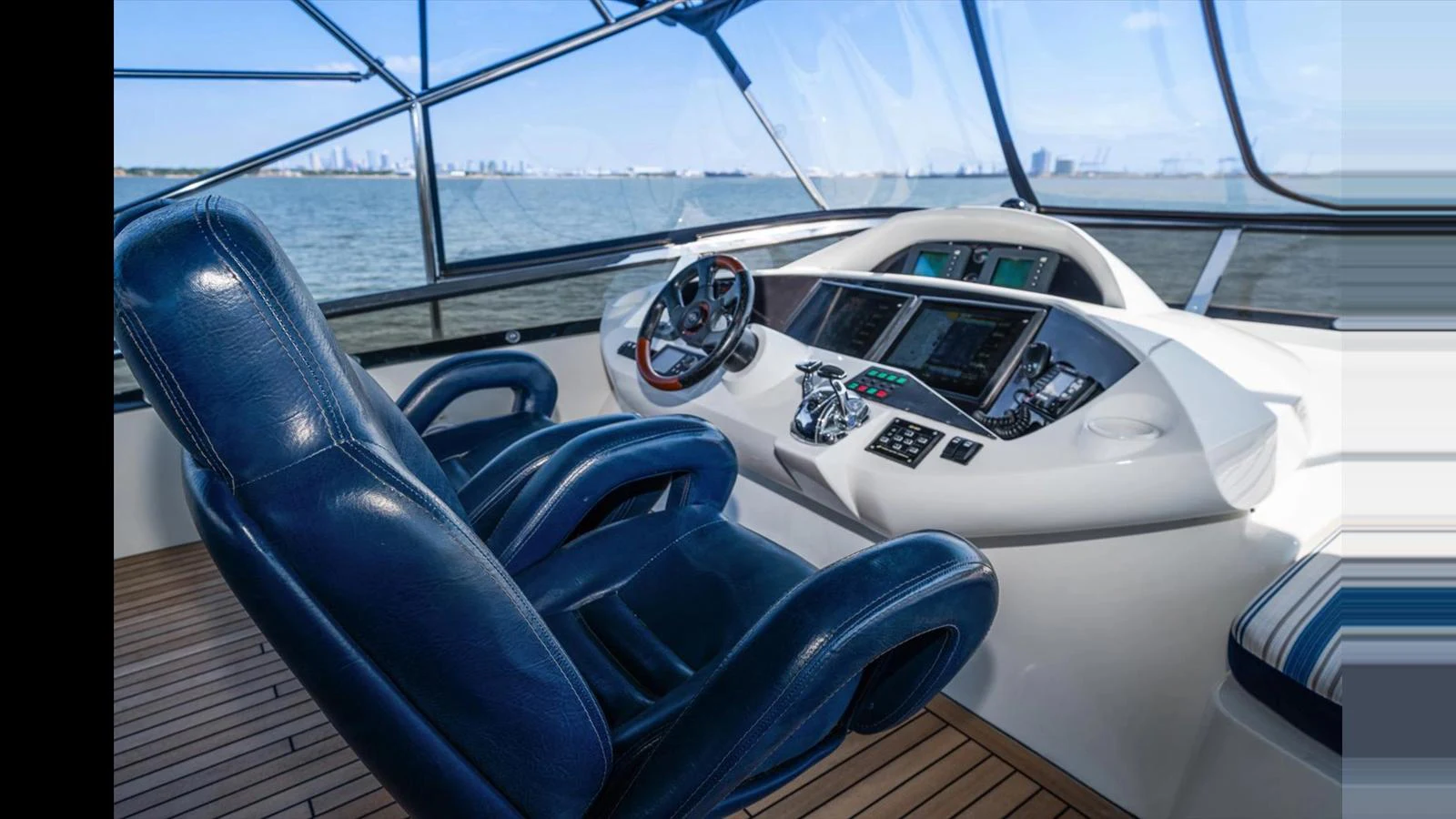 The helm station features plush seating and advanced navigation equipment, offering a commanding view of the water. aboard VANGUARD Yacht for Sale