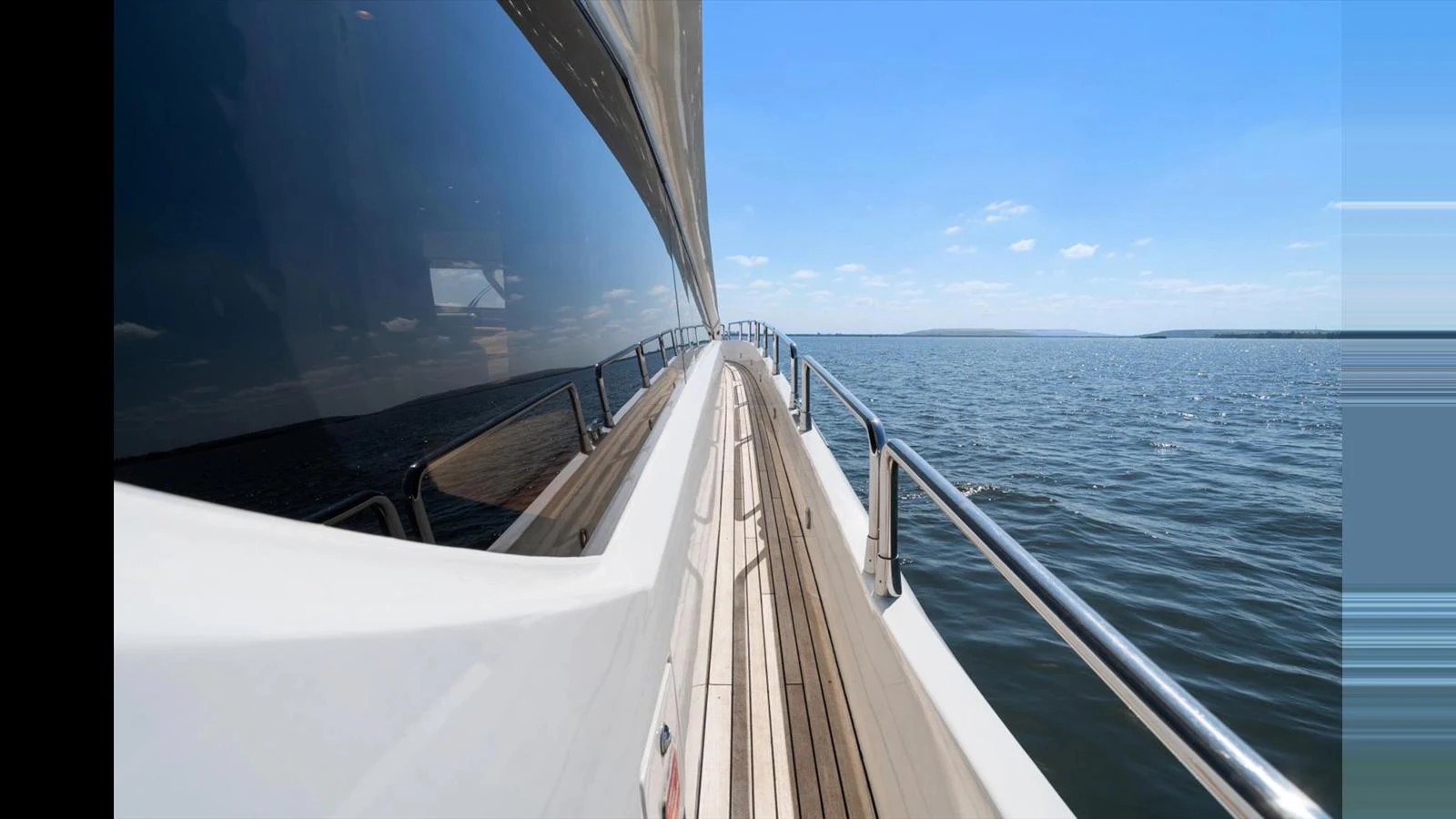 A sleek yacht cruising on calm waters under a clear blue sky. aboard VANGUARD Yacht for Sale