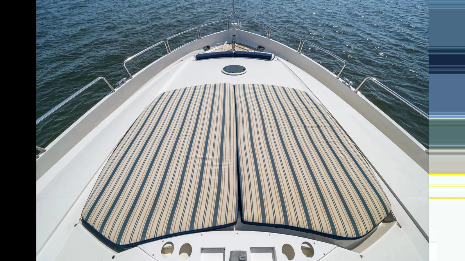 The foredeck features spacious striped sun pads for lounging while enjoying the view. aboard VANGUARD Yacht for Sale