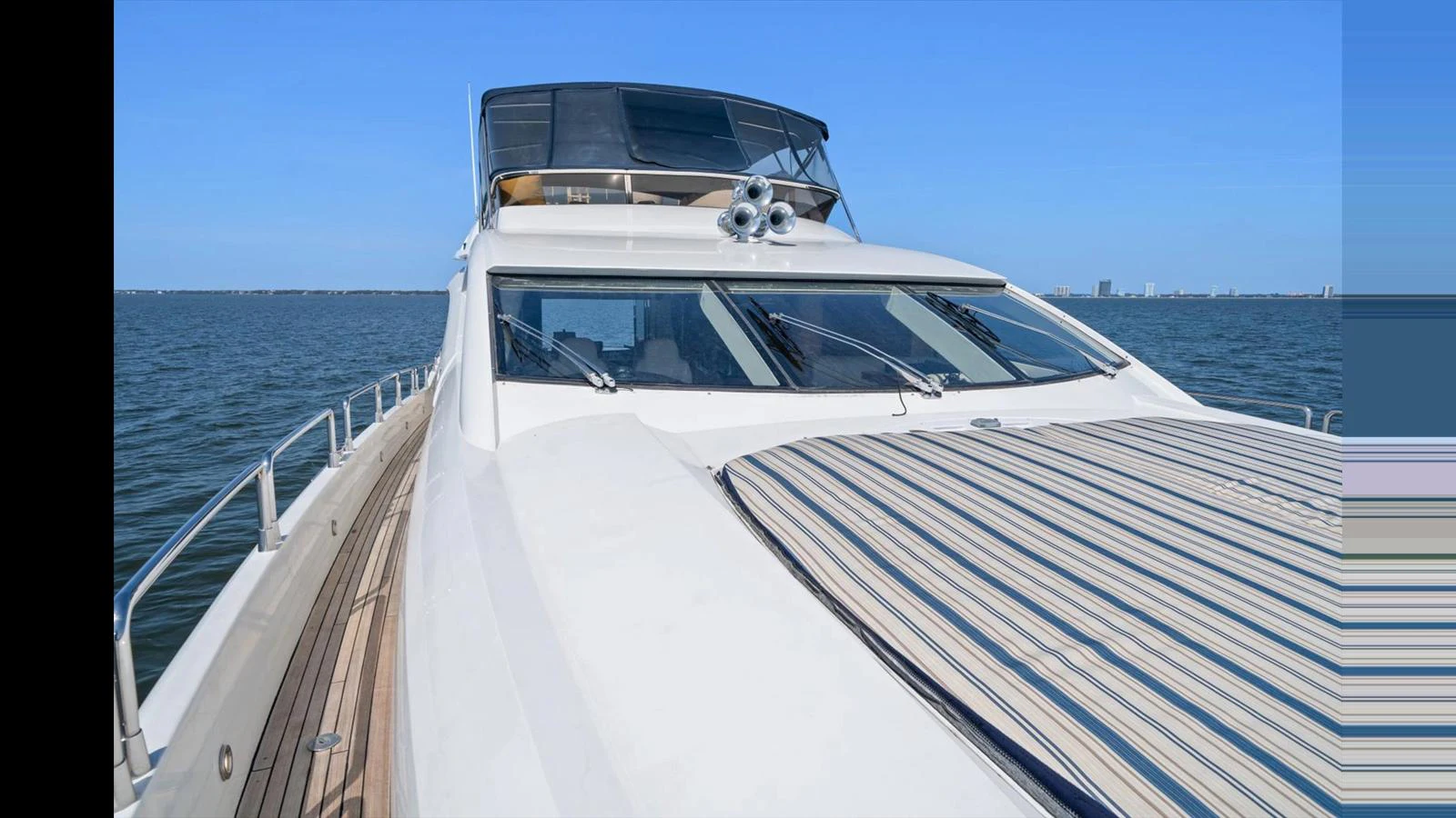 A sleek yacht cruising on calm waters with a clear blue sky in the background. aboard VANGUARD Yacht for Sale