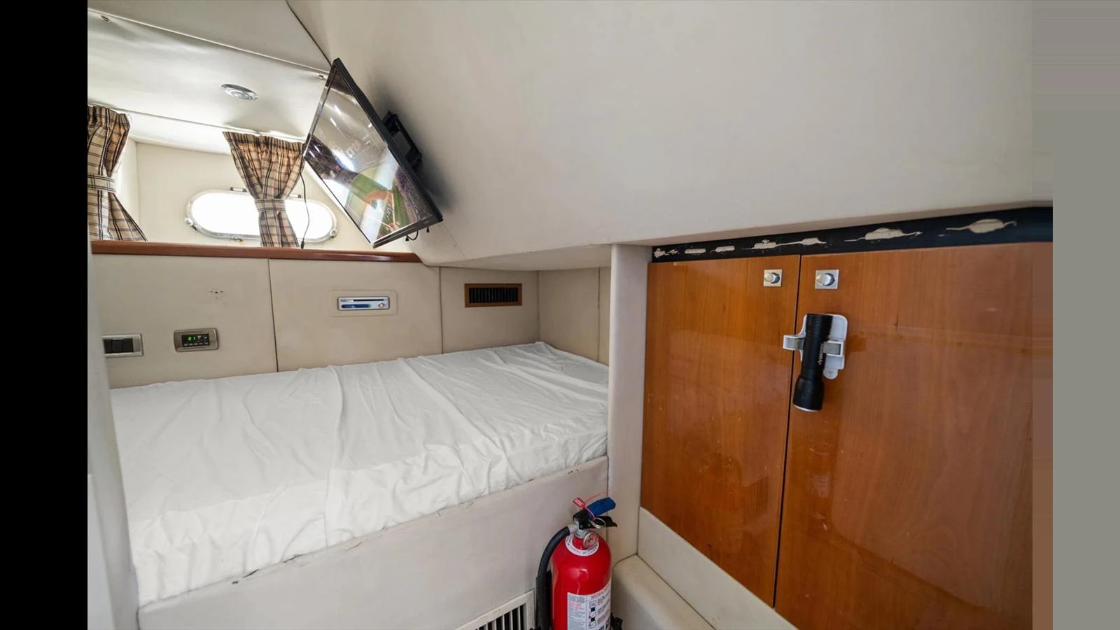 A cozy yacht cabin featuring a bed, a wall-mounted TV, and storage cabinets. aboard VANGUARD Yacht for Sale
