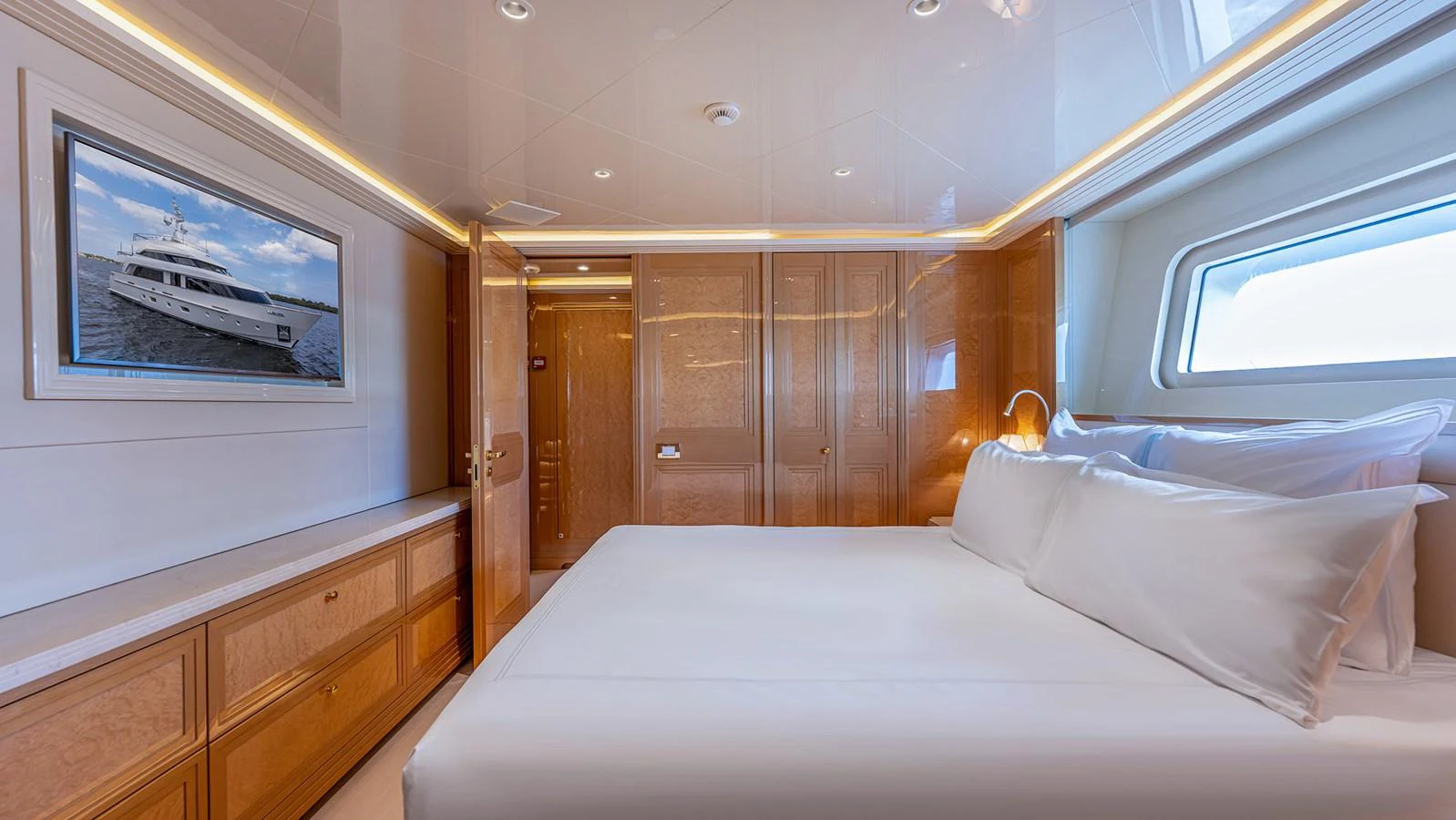 The stateroom features a luxurious bed with crisp white linens and elegant wooden cabinetry. aboard BETTY JANE Yacht for Sale