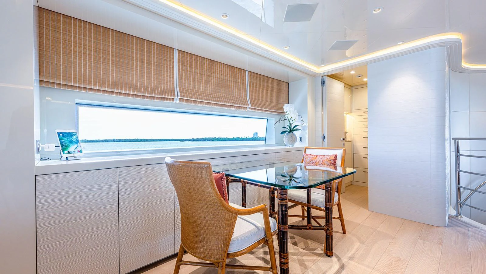The yacht's interior features a stylish dining area with a view of the sea through a large window. aboard BETTY JANE Yacht for Sale
