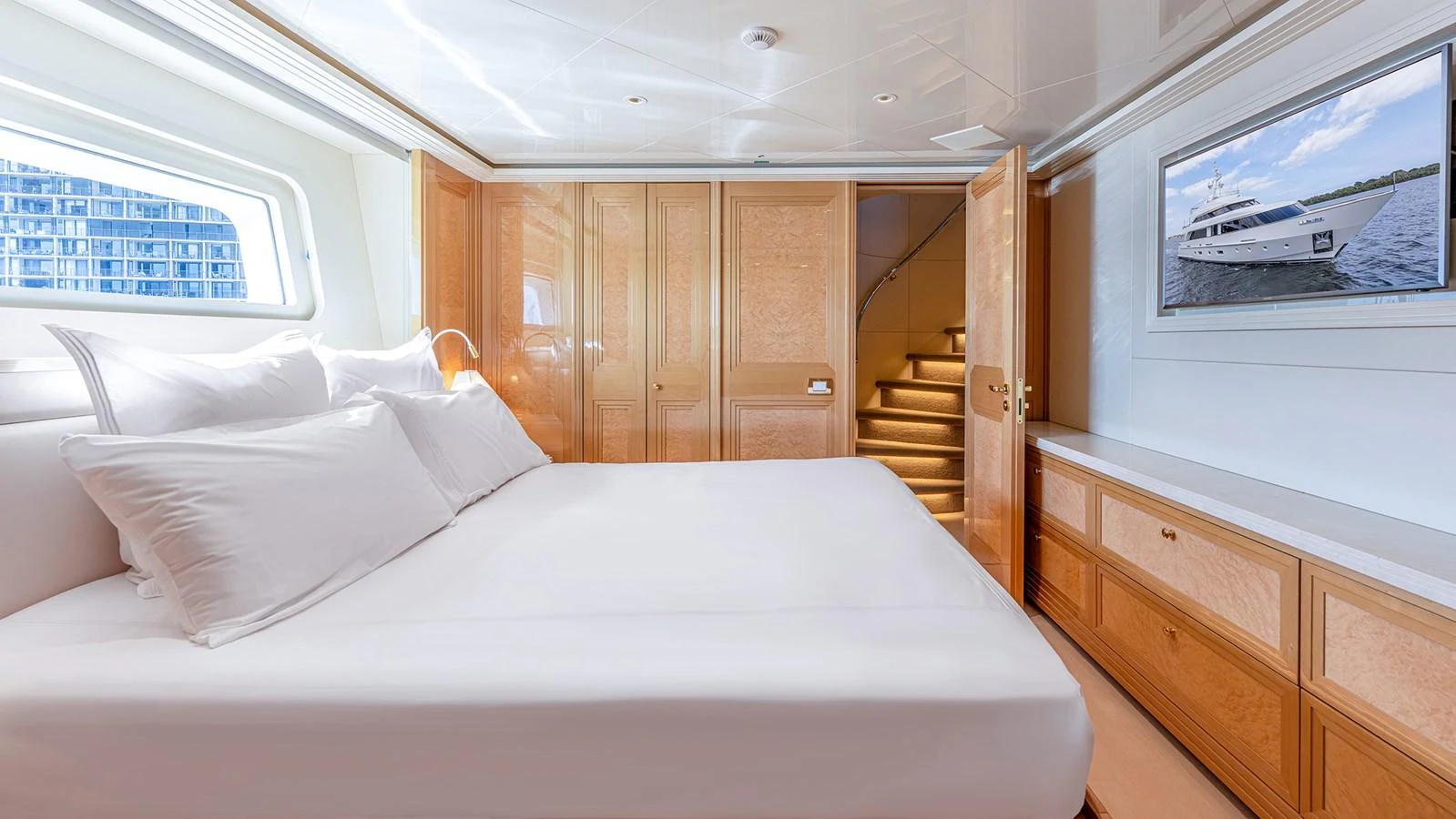 The stateroom features a large, comfortable bed with elegant wood finishes and a flat-screen TV. aboard BETTY JANE Yacht for Sale
