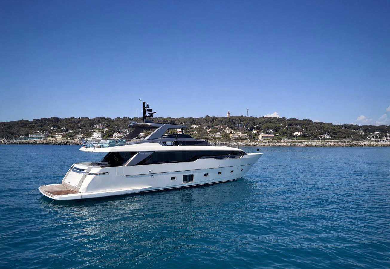 A sleek and modern yacht glides gracefully on calm blue waters with a scenic coastal backdrop. aboard KAPUSHA Yacht for Sale