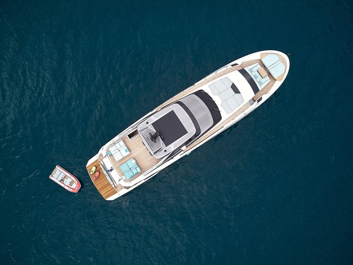 An aerial view of a sleek yacht cruising on calm blue waters, accompanied by a small tender. aboard KAPUSHA Yacht for Sale