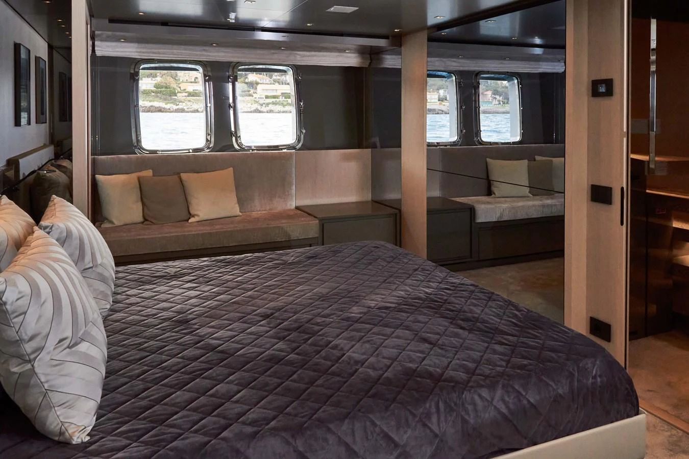 The stateroom features a luxurious bed with a view of the sea through large windows. aboard KAPUSHA Yacht for Sale