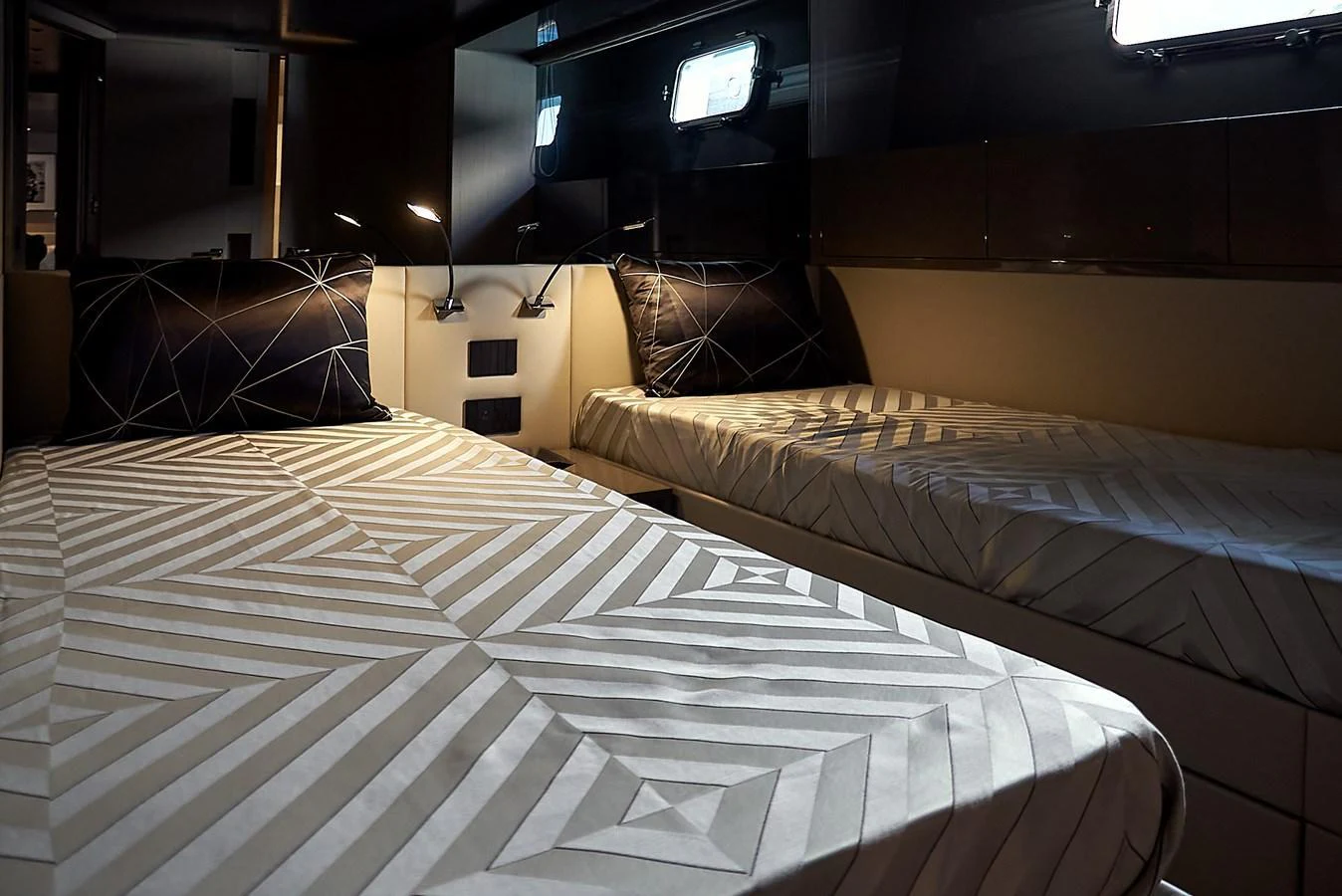 The guest stateroom features twin beds with modern geometric bedding and ambient lighting. aboard KAPUSHA Yacht for Sale