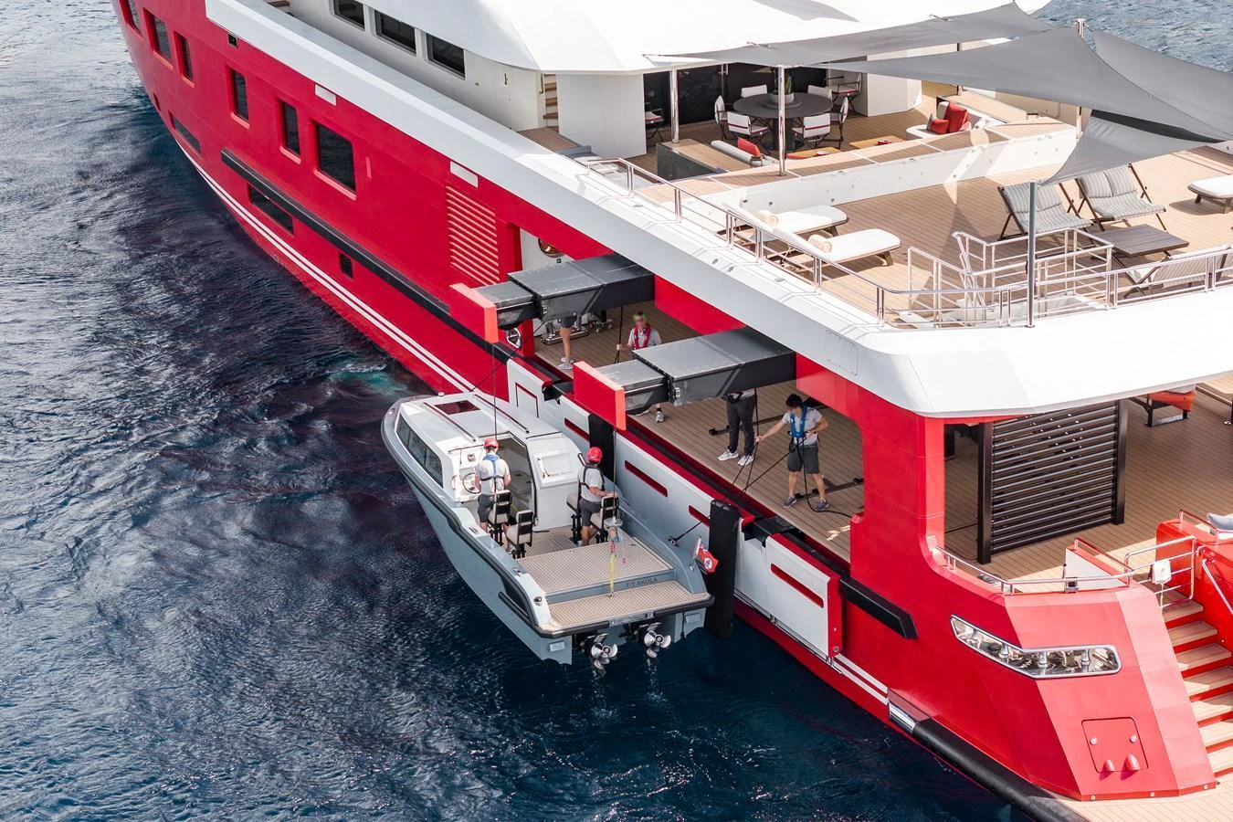 A striking red yacht with an open side garage and tender on the water. aboard AKULA Yacht for Sale