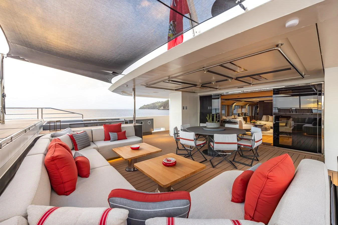 The aft deck features a spacious seating area with plush cushions and a dining table, perfect for outdoor relaxation and entertainment. aboard AKULA Yacht for Sale