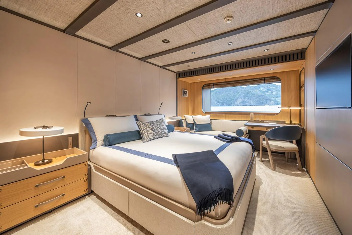The master stateroom features a luxurious bed, elegant furnishings, and a scenic window view. aboard AKULA Yacht for Sale