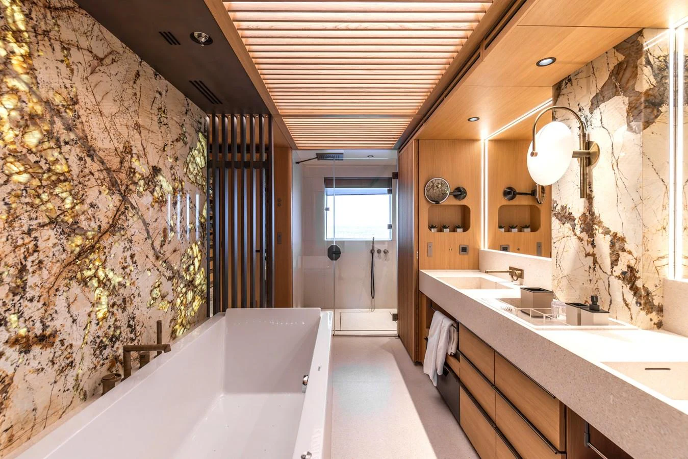 The luxurious bathroom features elegant marble walls, a spacious bathtub, and modern fixtures. aboard AKULA Yacht for Sale