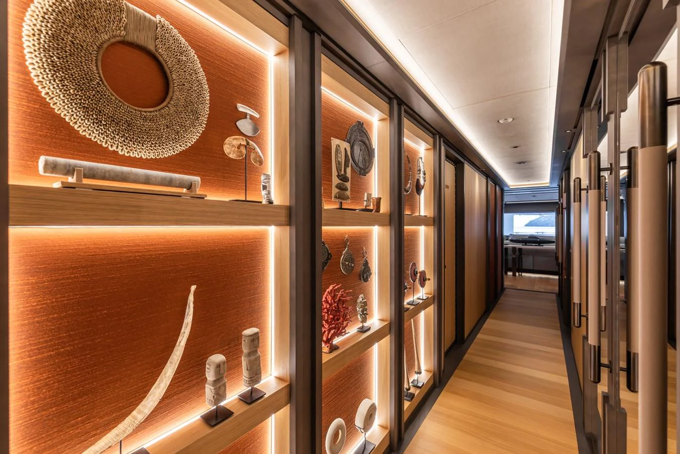 The yacht's hallway features an elegant display of art pieces and sculptures, illuminated by warm lighting. aboard AKULA Yacht for Sale