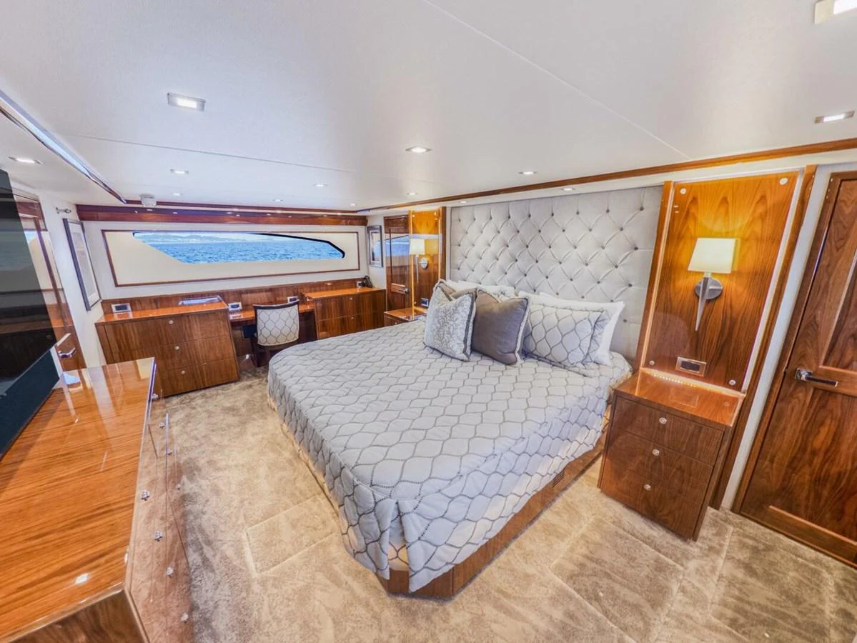 The master stateroom features a luxurious bed with elegant wood finishes and ample natural light. aboard MARLIN MAGIC Yacht for Sale