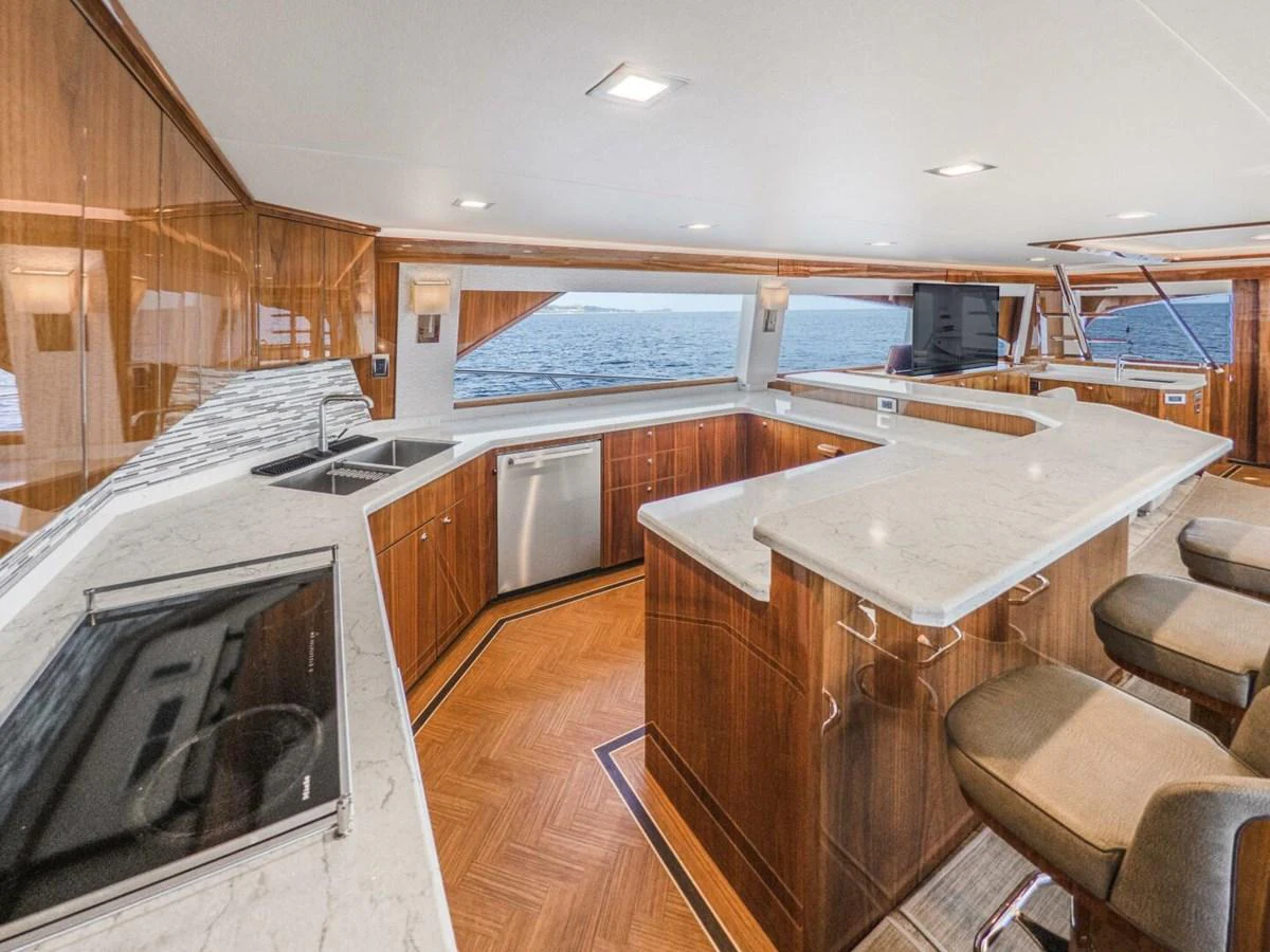 The yacht's galley features elegant wood cabinetry, modern appliances, and ample counter space with a view of the sea. aboard MARLIN MAGIC Yacht for Sale