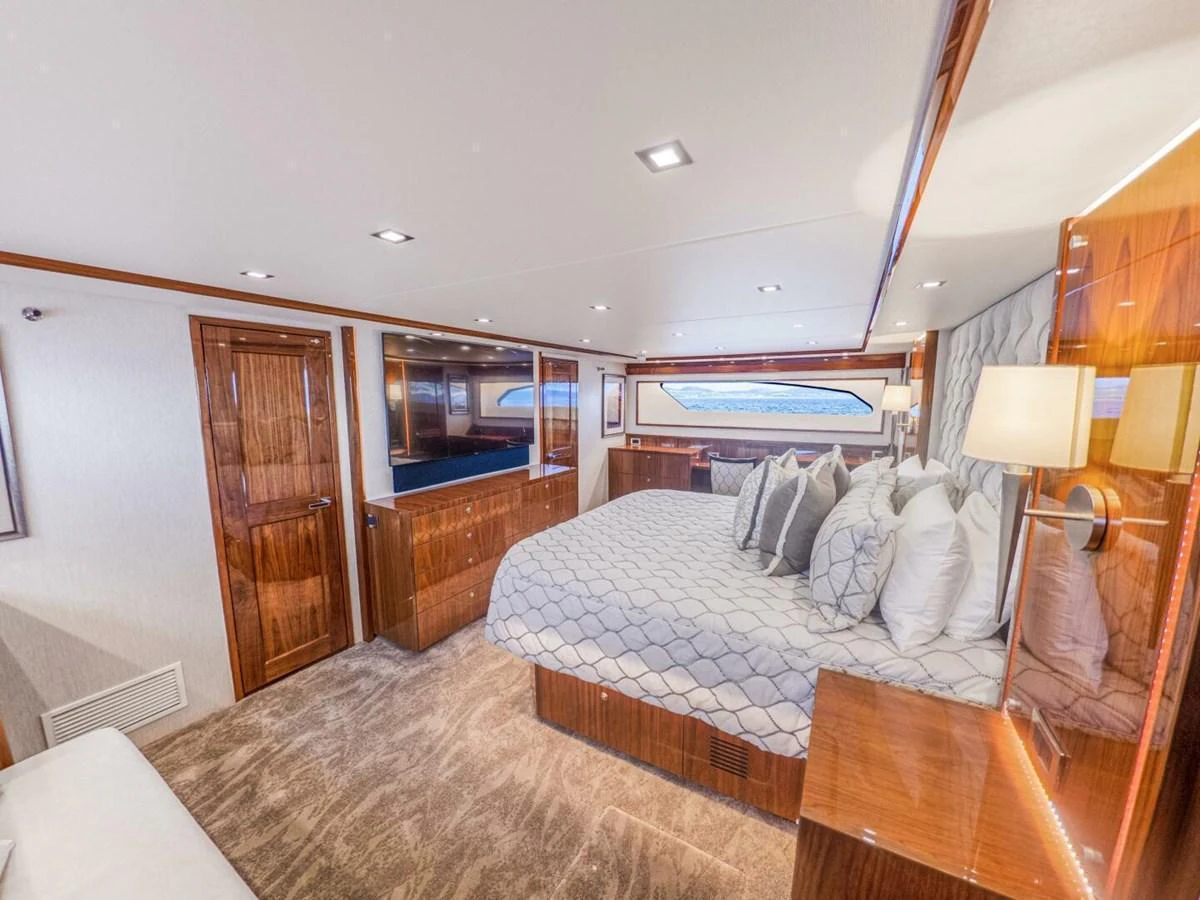 The master stateroom features a luxurious bed with elegant wood finishes and ample natural light. aboard MARLIN MAGIC Yacht for Sale