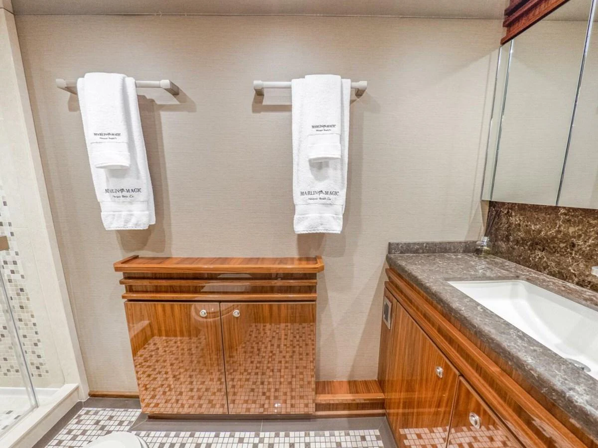 The yacht's bathroom features elegant wood cabinetry and a sleek countertop with a modern sink. aboard MARLIN MAGIC Yacht for Sale