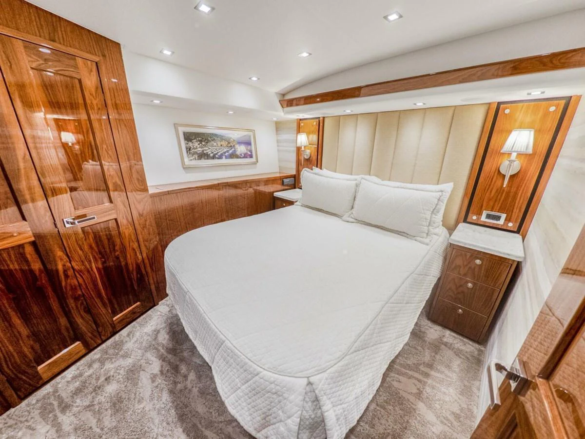 The stateroom features a luxurious bed with elegant wooden finishes and soft lighting. aboard MARLIN MAGIC Yacht for Sale