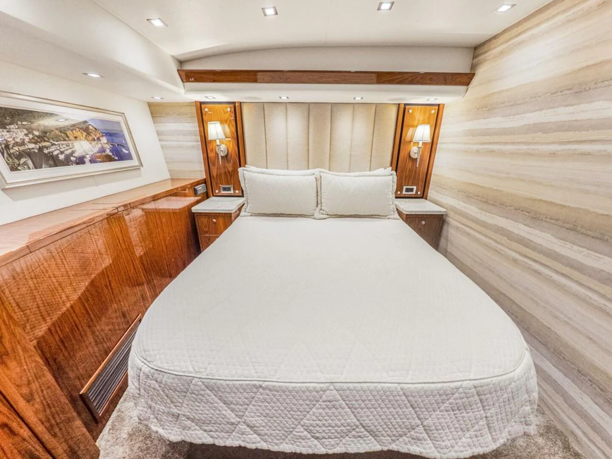 The stateroom features a luxurious bed with elegant wood accents and modern lighting. aboard MARLIN MAGIC Yacht for Sale