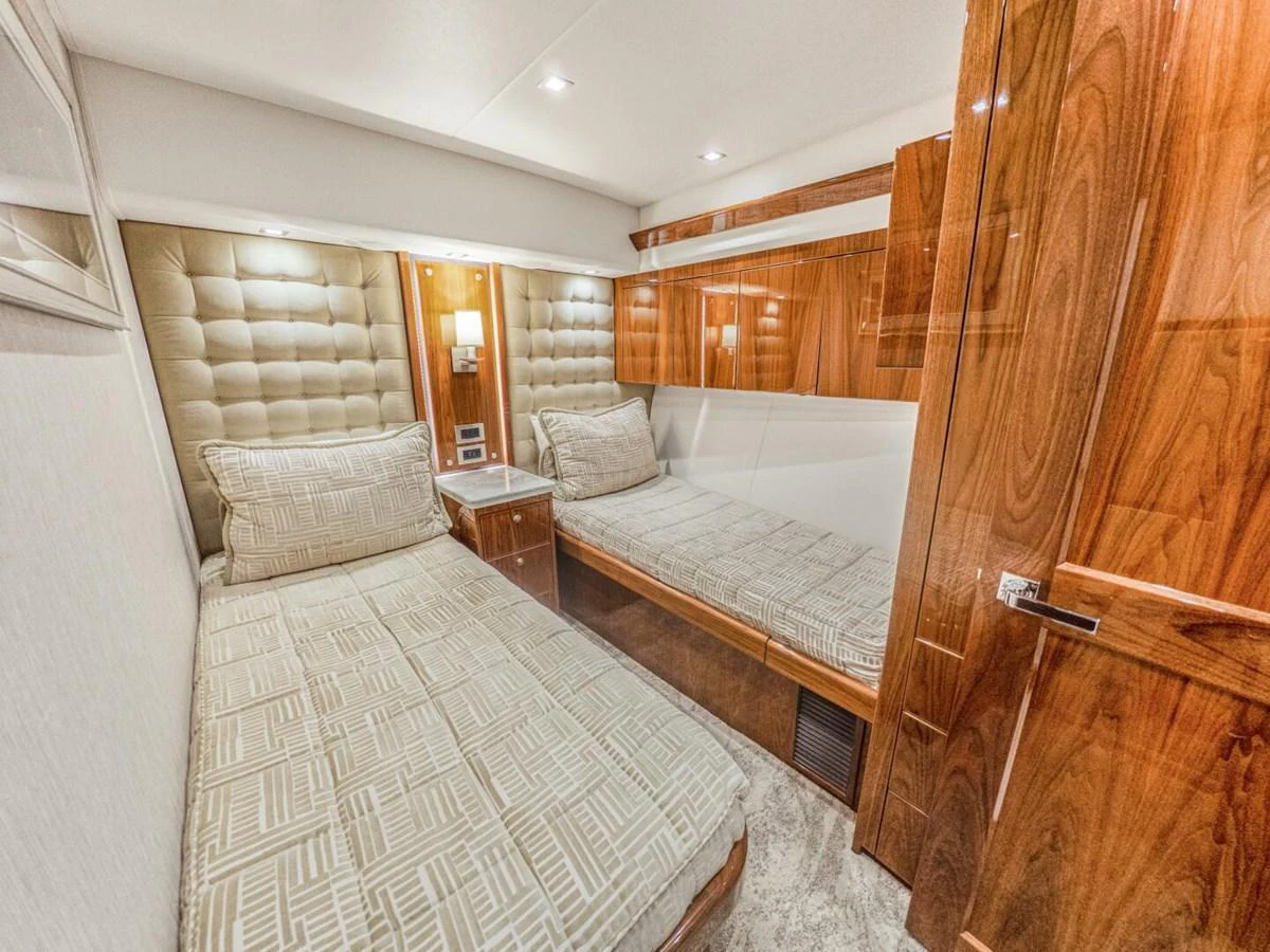 This cozy twin stateroom features plush bedding and elegant wood finishes, offering a comfortable retreat. aboard MARLIN MAGIC Yacht for Sale