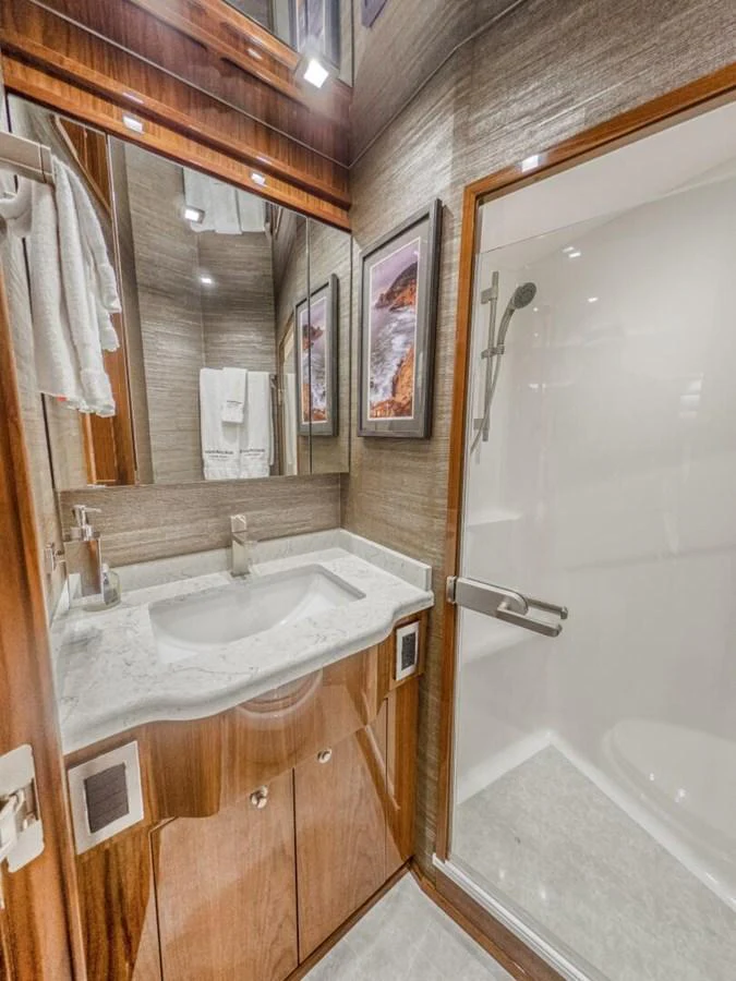 The yacht's bathroom features a sleek design with a modern shower and elegant wooden cabinetry. aboard MARLIN MAGIC Yacht for Sale
