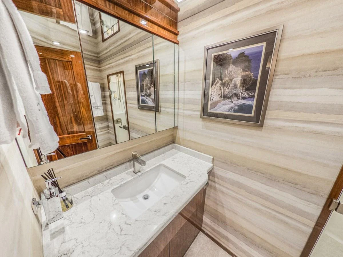 The yacht's bathroom features a sleek marble countertop and elegant wood accents. aboard MARLIN MAGIC Yacht for Sale