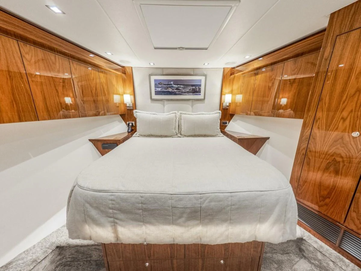 The stateroom features a luxurious bed with elegant wood paneling and soft lighting. aboard MARLIN MAGIC Yacht for Sale