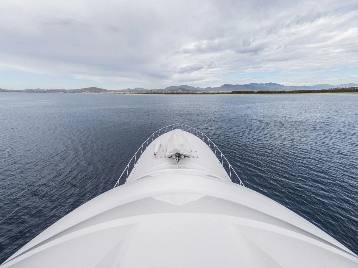 The yacht's bow gracefully cuts through calm waters under a serene sky. aboard MARLIN MAGIC Yacht for Sale