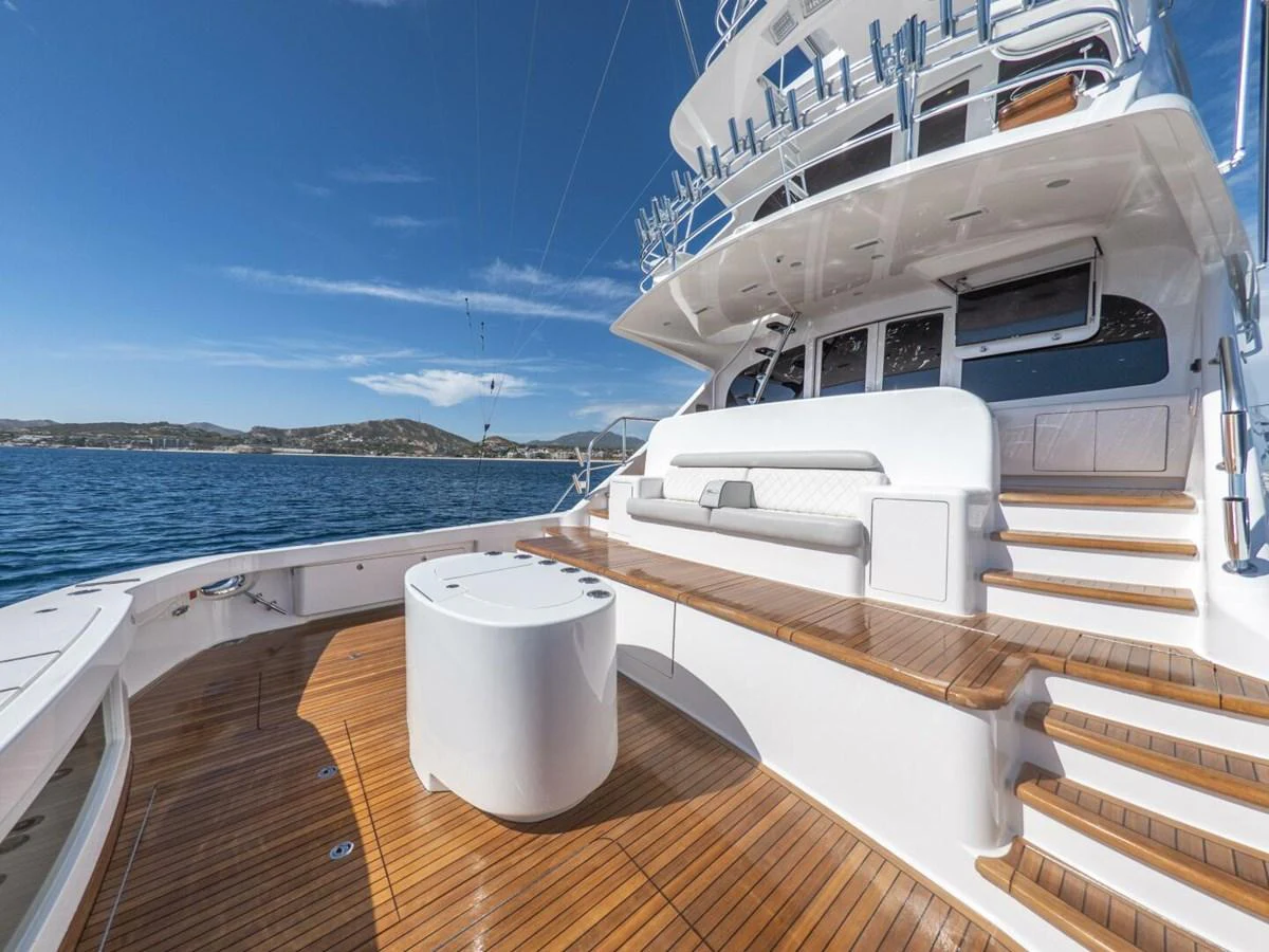 The aft deck features elegant teak flooring and comfortable seating with a scenic ocean backdrop. aboard MARLIN MAGIC Yacht for Sale