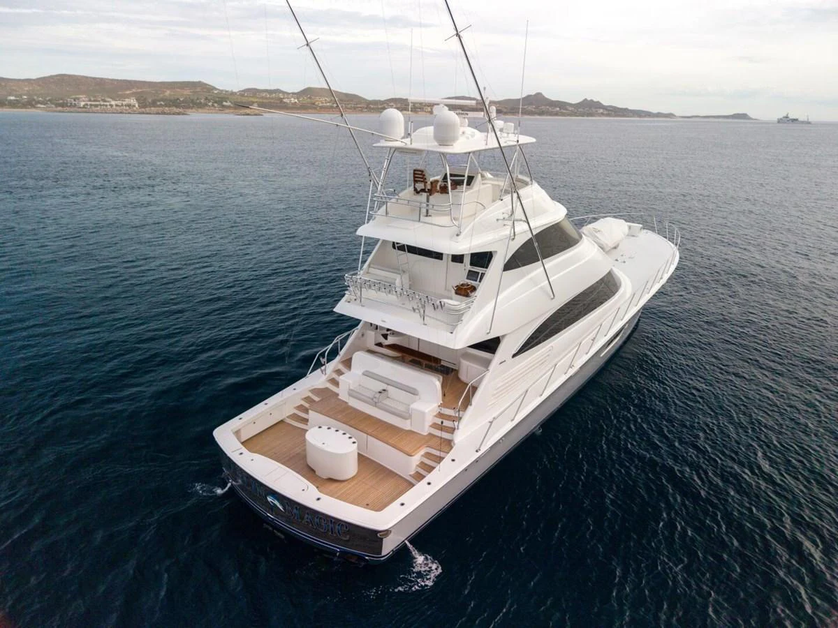 A sleek yacht cruises through calm waters, showcasing its spacious aft deck and multiple levels. aboard MARLIN MAGIC Yacht for Sale