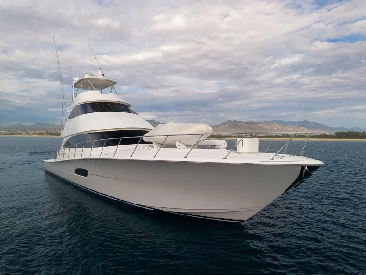 A sleek and modern yacht glides gracefully on calm waters under a partly cloudy sky. aboard MARLIN MAGIC Yacht for Sale