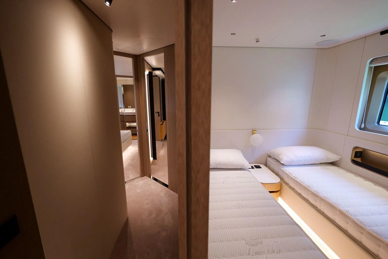 The image showcases a cozy guest cabin with twin beds and a view into an en-suite bathroom. aboard SEA STAR Yacht for Sale