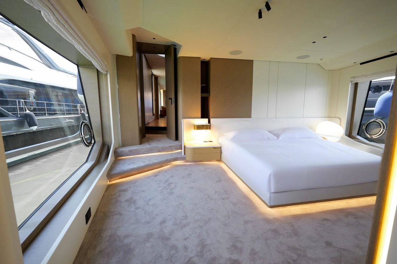 The stateroom features a spacious bed with modern lighting and large windows offering a view of the marina. aboard SEA STAR Yacht for Sale