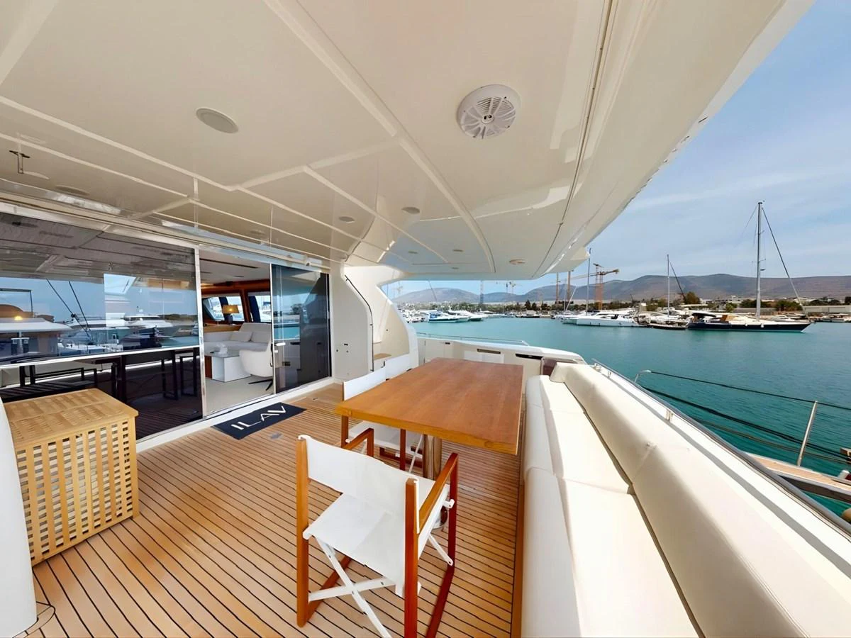 The aft deck features a spacious seating area with a wooden dining table, perfect for alfresco dining while enjoying the marina view. aboard M/Y ILAV Yacht for Sale
