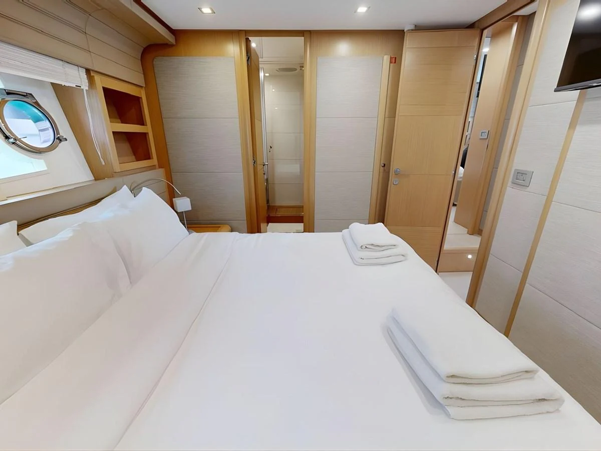 The stateroom features a comfortable bed with crisp white linens and modern wooden accents. aboard M/Y ILAV Yacht for Sale