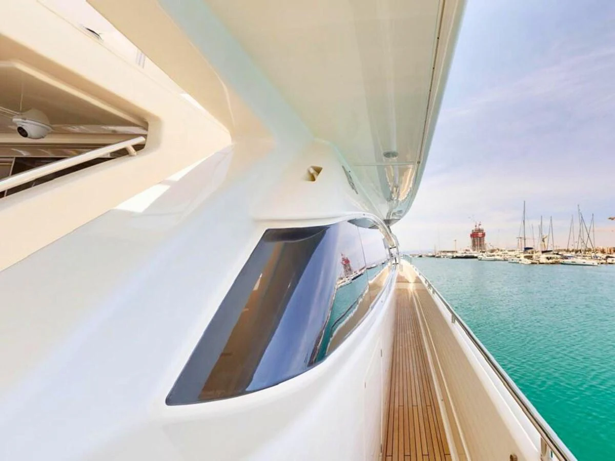 The sleek exterior of the yacht is showcased with a view of the deck and marina in the background. aboard M/Y ILAV Yacht for Sale