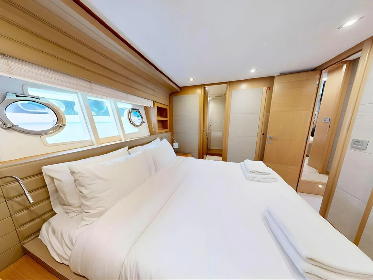 The stateroom features a luxurious bed with plush linens and ample natural light from the porthole windows. aboard M/Y ILAV Yacht for Sale
