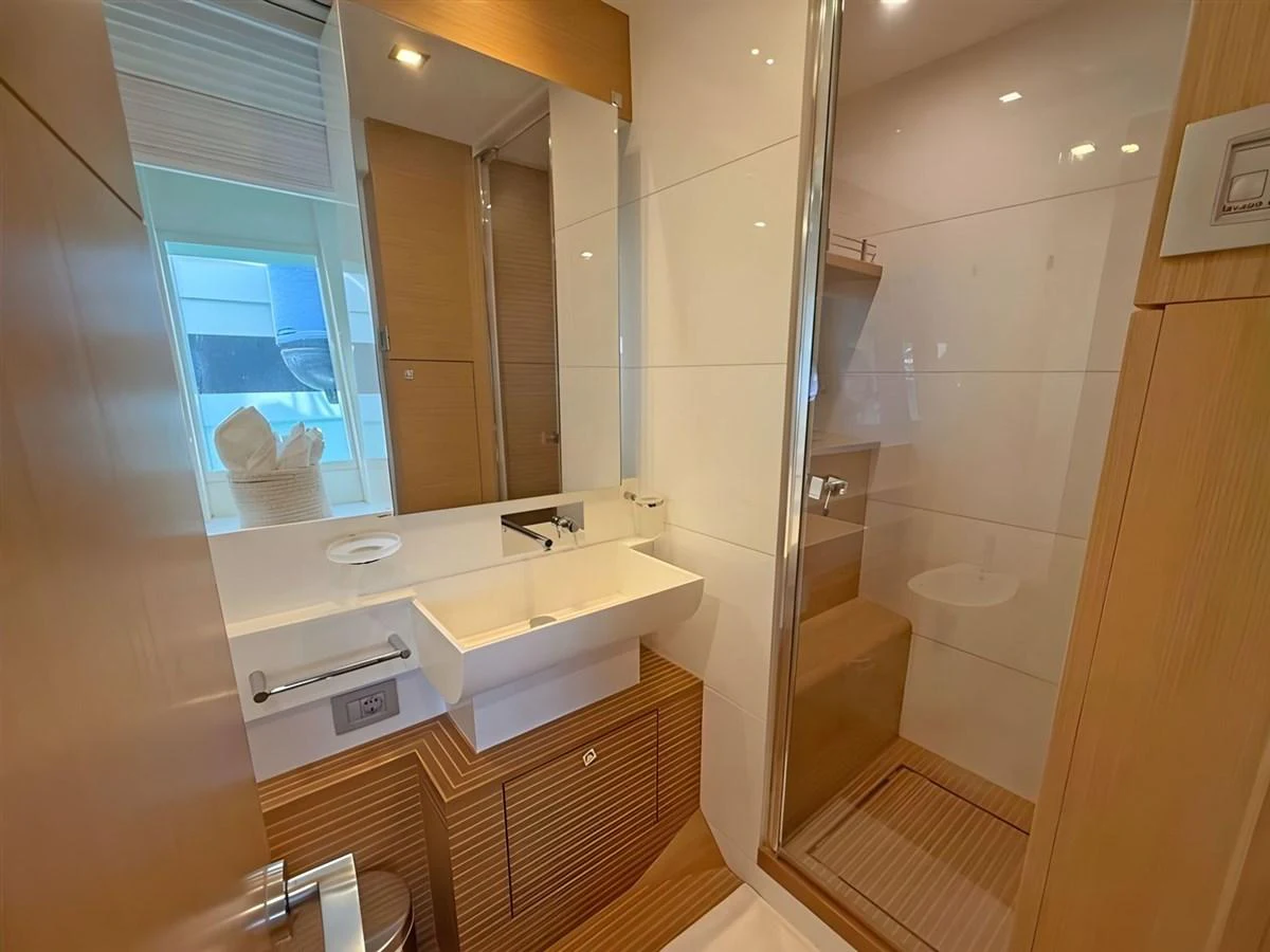 A sleek and modern yacht bathroom with wood accents and a glass-enclosed shower. aboard M/Y ILAV Yacht for Sale