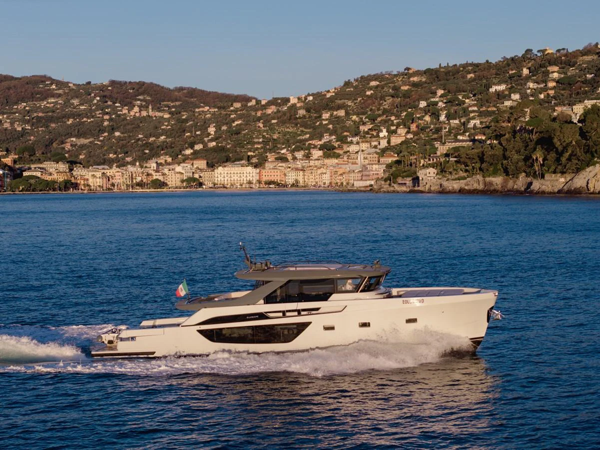 A sleek yacht cruises along the coastline under a clear sky. aboard EOLINO Yacht for Sale