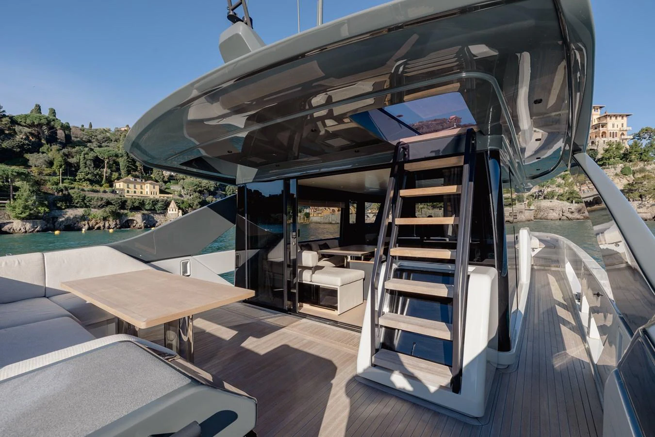 The aft deck features a spacious seating area with a dining table and access to the upper deck via a sleek staircase. aboard EOLINO Yacht for Sale