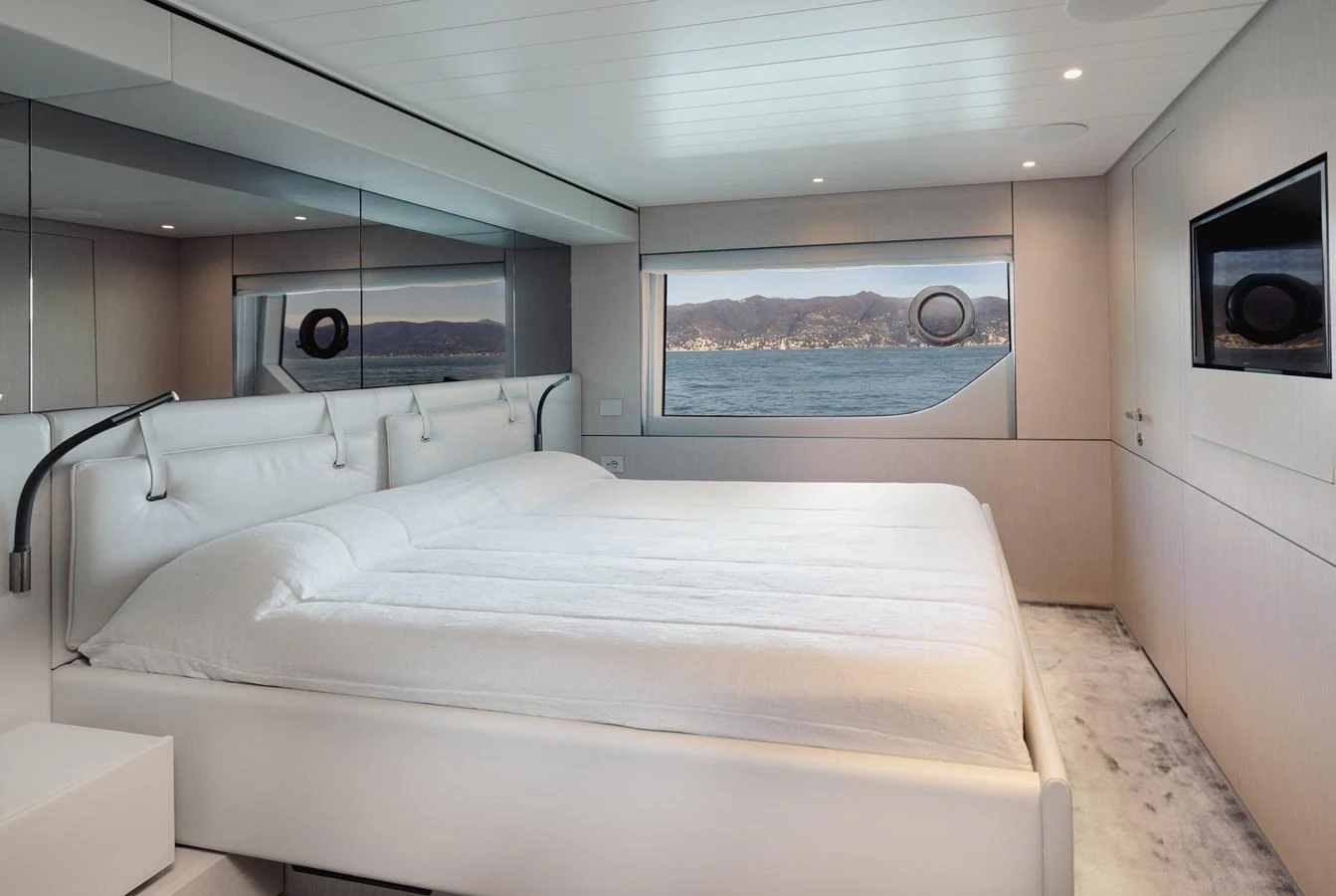 A luxurious stateroom featuring a large bed with a scenic view through the window. aboard EOLINO Yacht for Sale