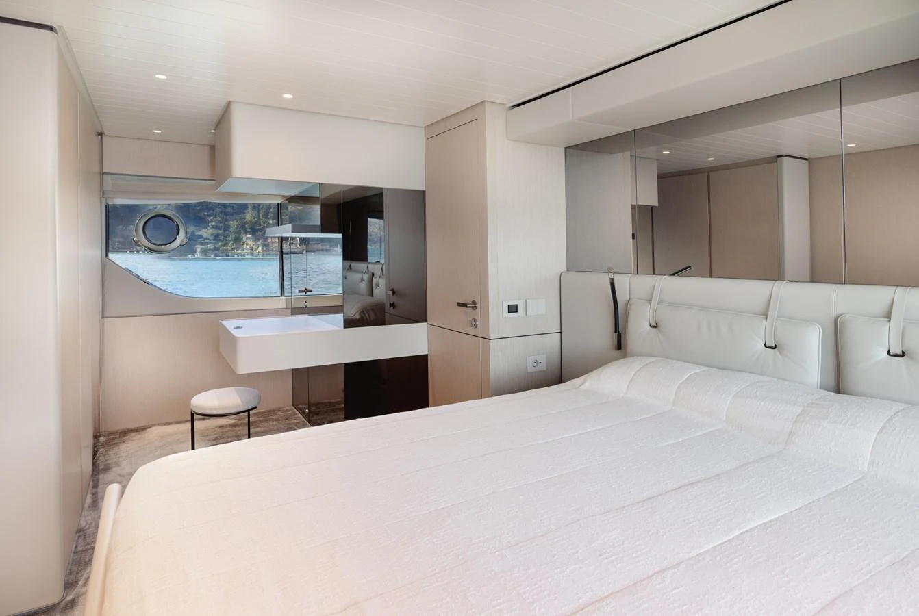 The stateroom features a luxurious bed, modern furnishings, and a scenic window view. aboard EOLINO Yacht for Sale