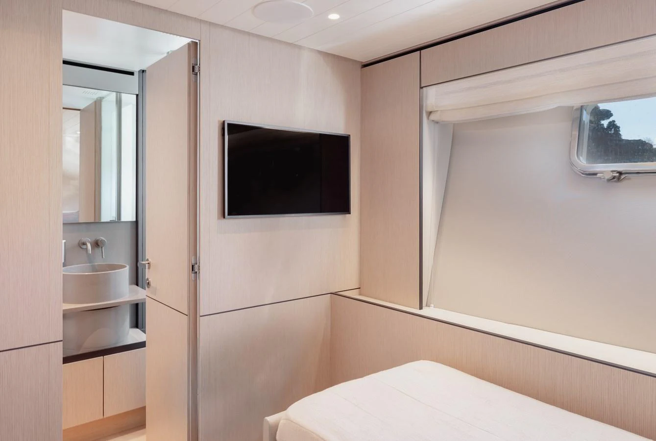 A cozy stateroom featuring a comfortable bed, a wall-mounted TV, and an ensuite bathroom. aboard EOLINO Yacht for Sale