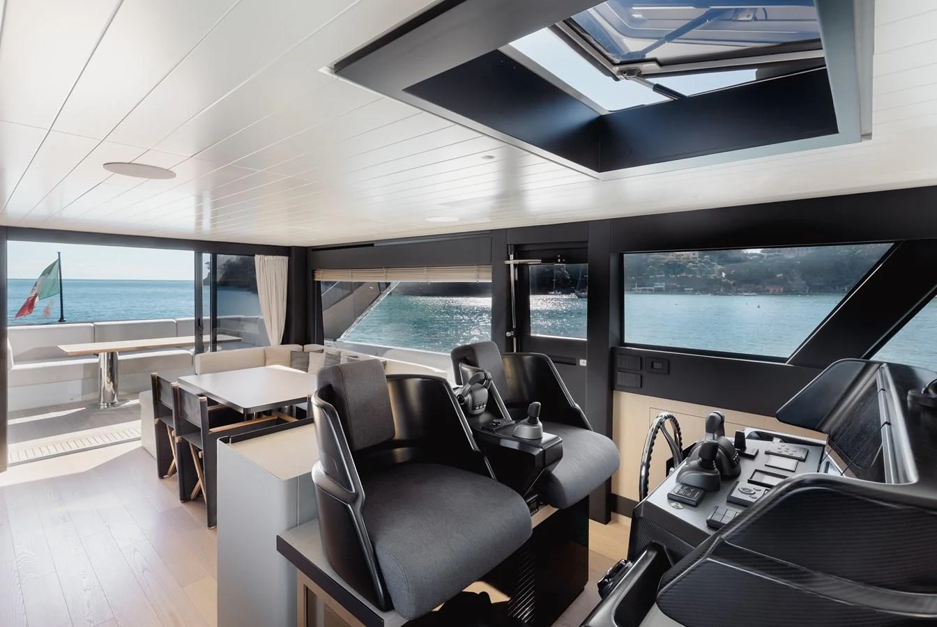 The helm area features modern controls with a spacious and well-lit dining area in the background. aboard EOLINO Yacht for Sale
