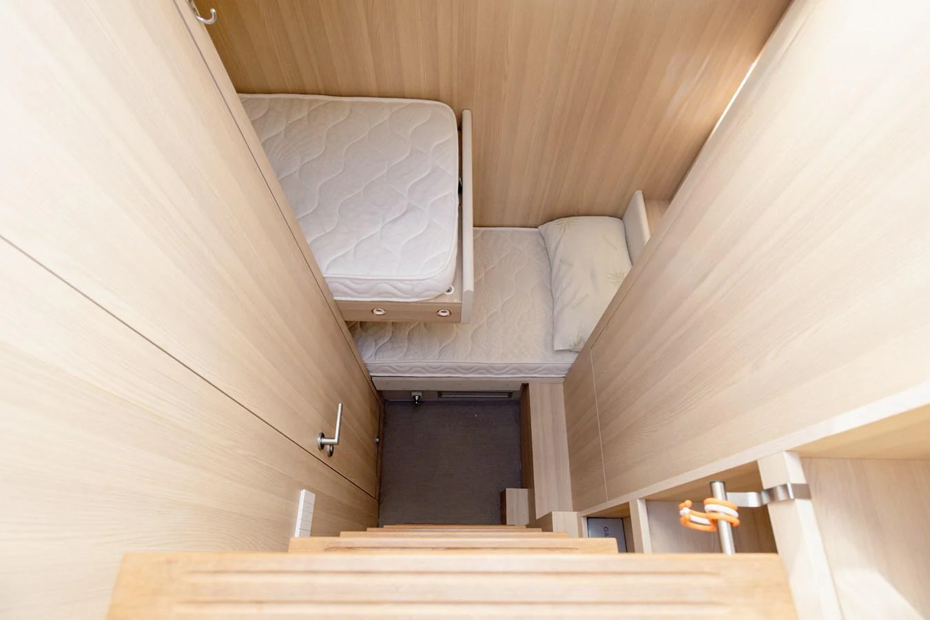 A cozy bunk room with light wood paneling and two single beds. aboard EOLINO Yacht for Sale