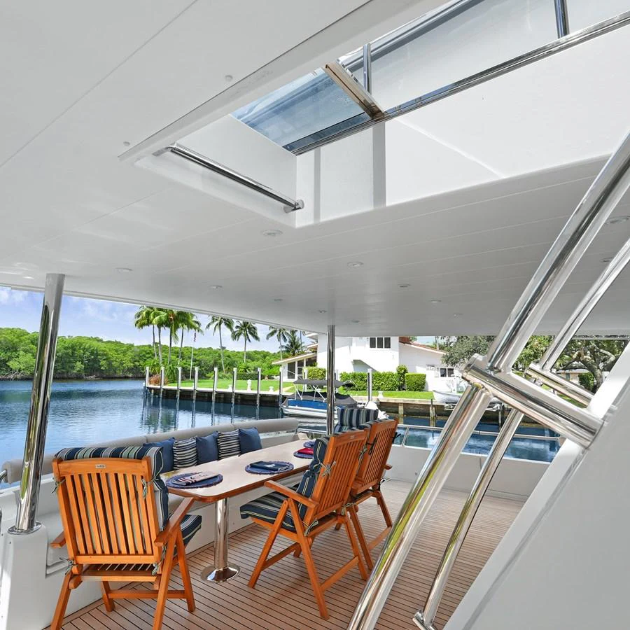 The aft deck features a comfortable dining area with a scenic view of the water and lush greenery. aboard MILES AWEIGH Yacht for Sale